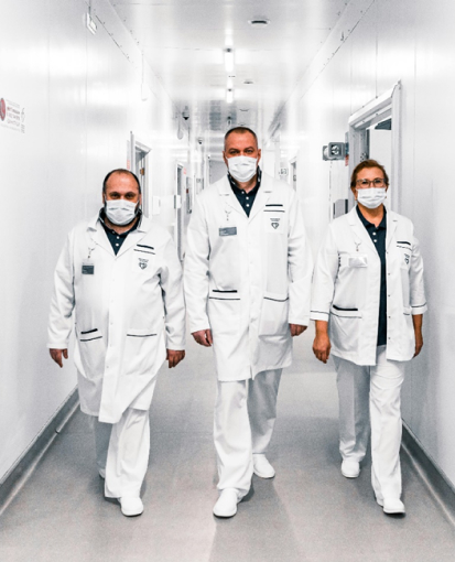 Three doctors in lab coats walking in a hallway 