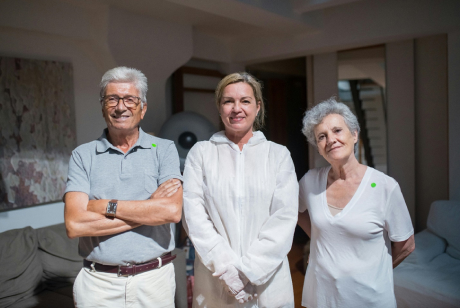 A family picture of elderly dad, their middle aged daughter and elderly mom smiling. 